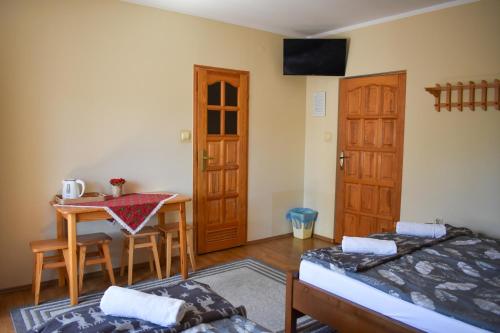 a room with a bed and a table and a door at Pokoje Gościnne u Wioli in Jurgów