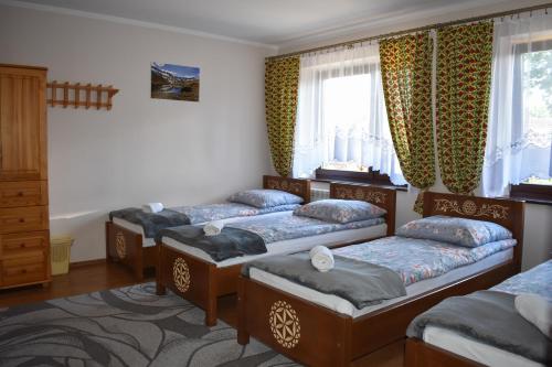 a bedroom with three beds and a window at Pokoje Gościnne u Wioli in Jurgów