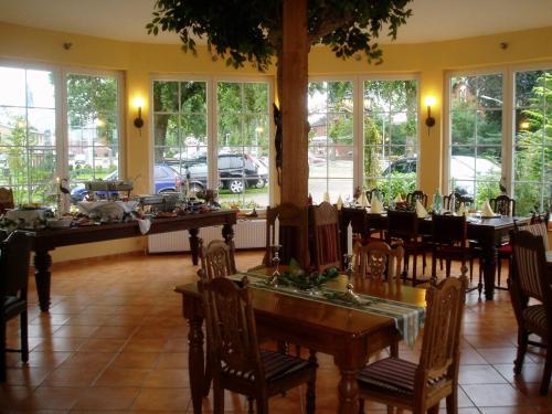 a dining room with tables and chairs and windows at Das Romantische Landhaus in Kropp