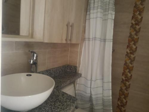 a bathroom with a white sink and a shower curtain at Beautiful Cozy House - Hermosa Casa Acogedora in Ibagué