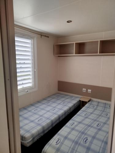 zwei Betten in einem kleinen Zimmer mit Fenster in der Unterkunft Mobil home dans camping 3 étoiles in Saint-Papoul