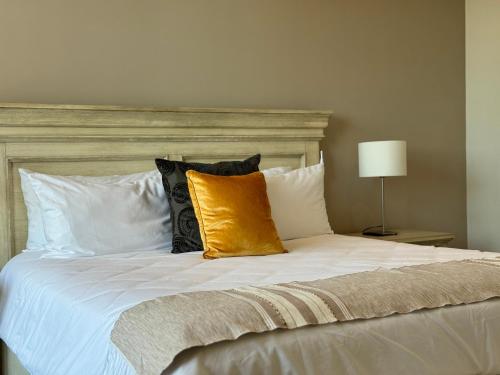 a large bed with white pillows and a yellow pillow at Suites Lassa in Ensenada