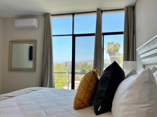 a bedroom with a bed with pillows and a large window at Suites Lassa in Ensenada