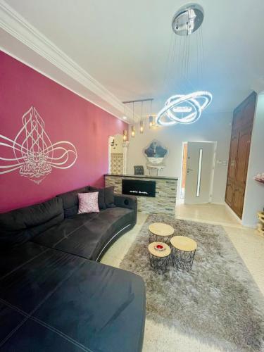 a living room with a black couch and a pink wall at Dar Misk Elil in Bizerte