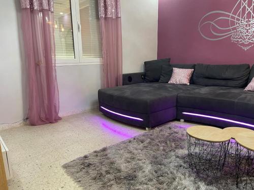 a living room with a black couch and purple walls at Dar Misk Elil in Bizerte