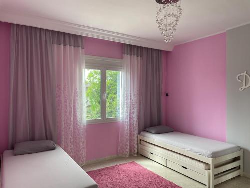 a pink bedroom with two beds and a window at Dar Misk Elil in Bizerte