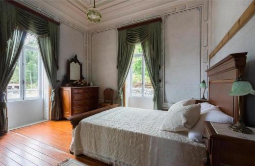 a bedroom with a large bed and two windows at Quinta da Capela in Viana do Castelo