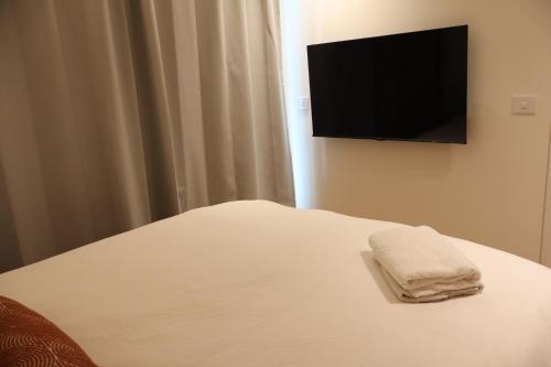 a bed with a towel on it with a flat screen tv at Lotus Suite 42 in Eilat