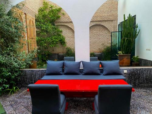 a red bed in a courtyard with two chairs at Riad Dar Hania en Exclusivité in Marrakech