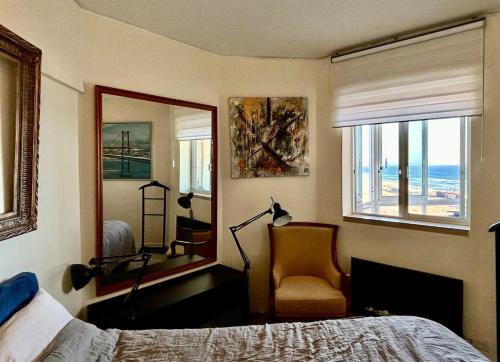 a bedroom with a bed and a mirror and a chair at Frente práia 8ºandar-parking grátis-surf&naturismo in Costa da Caparica