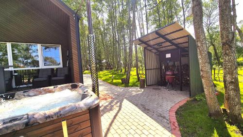 a building with a hot tub next to a tree at Župė Dream House with jacuzzi and sauna in Klaipėda