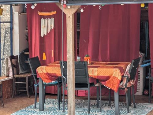 une table avec des chaises et un rideau rouge dans l'établissement Chambre d'hôtes, à Briatexte