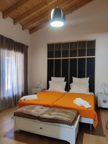 a bedroom with a large bed with an orange blanket at Pátio do Forno in Mértola