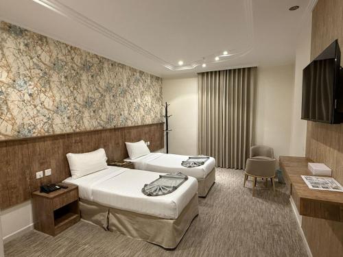 a hotel room with two beds and a tv at فندق الخلفاء الماسي الفندقية in Makkah