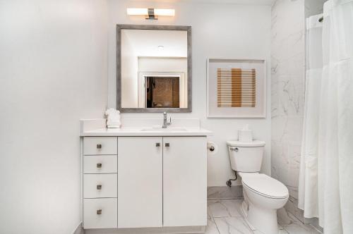 a white bathroom with a toilet and a mirror at The Saddlery-Playlist-2 Units-Walk to Broadway in Nashville