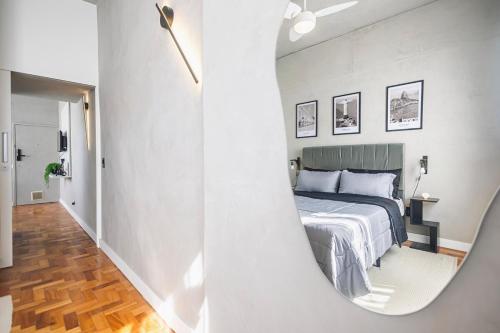 a mirror reflecting a bedroom with a bed and a hallway at Apê moderno no Largo do Machado in Rio de Janeiro