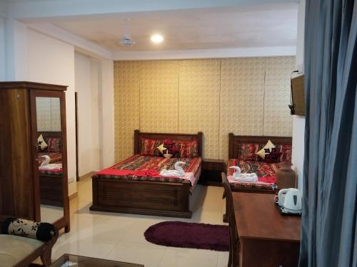 a bedroom with two beds and a desk and a mirror at New Kings Gate Airport Transit Hotel in Katunayake