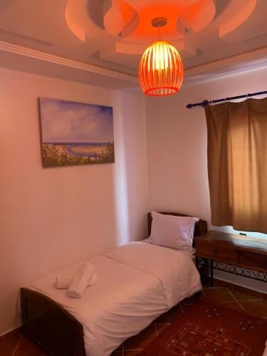 a bedroom with a bed and a lamp and a window at Le grand château Vue sur Mer uniquement les familles in Oualidia