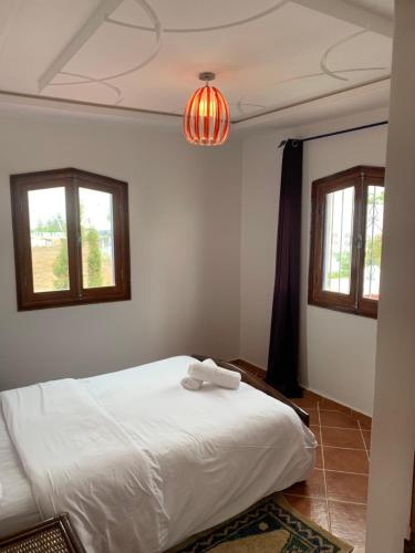 a bedroom with a white bed and two windows at Le grand château Vue sur Mer uniquement les familles in Oualidia