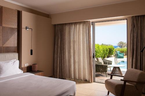 a hotel room with a bed and a sliding glass door at KRESTEN ROYAL Euphoria Resort in Kallithea Rhodes
