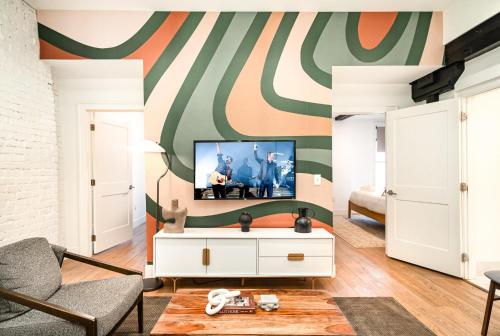 a living room with a tv on a wall at The Saddlery - The Vault - 2 Min Walk to Broadway in Nashville