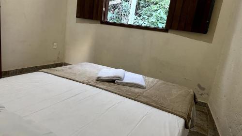 una camera da letto con un letto con due asciugamani sopra di Chalé de 2 quartos no Centro da Serra do Cipó a Serra do Cipo