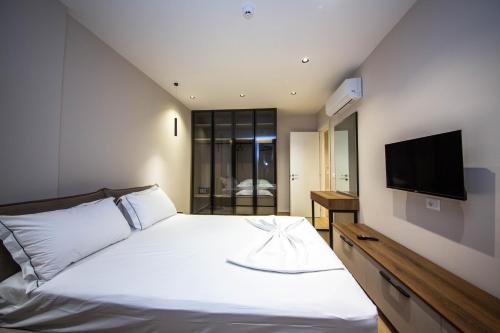 Un dormitorio con una cama blanca y un televisor de pantalla plana. en Apartments Ajdens Place, en Vlorë