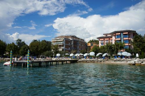 a dock with chairs and umbrellas on a beach at Front Lake Apartment Bardolino in Bardolino