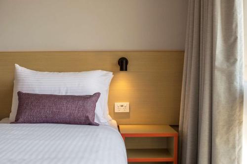 a bed with a purple pillow next to a window at Nightcap at Waltzing Matilda Hotel in Springvale