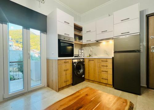 Una cocina con gabinetes blancos y un refrigerador negro. en Blue Studio Houses, en Samos