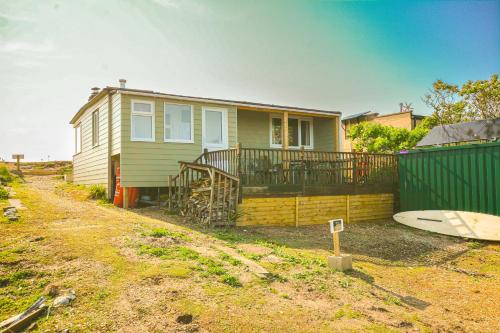 a house with a fence and a surfboard in front of it at beautiful eco-beach house next to bird reserve in Snettisham