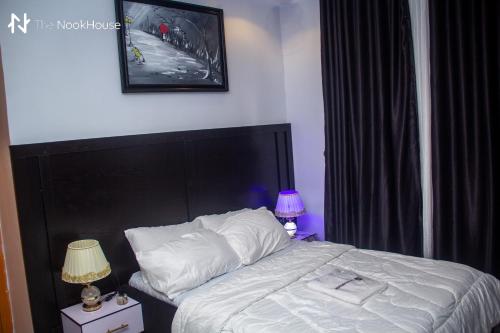 a bedroom with a bed with white sheets and two lamps at The NookHouse in Calabar