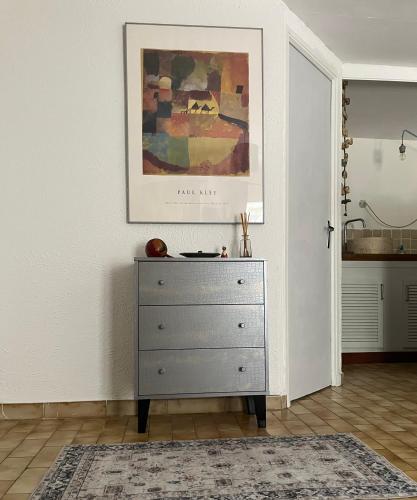 une commode dans une pièce avec un tableau sur le mur dans l'établissement Studio avec terrasse sur cour, authentique, calme, à Avignon