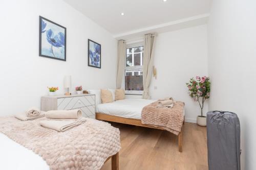 a white bedroom with two beds and a window at Open Mind Property- Stylish 3BR, HotTub & Parking in Portsmouth