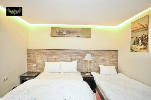two beds in a hotel room with white sheets at Comfort in Cairo