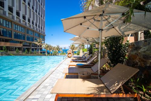 a row of chairs with umbrellas next to a swimming pool at PEARL APEC MANDALA in Mui Ne
