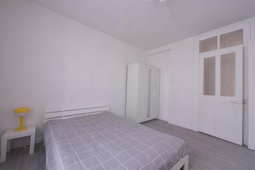 a white bedroom with a bed and a chair at Appartement T3,5 Fairey in Bellegarde-sur-Valserine