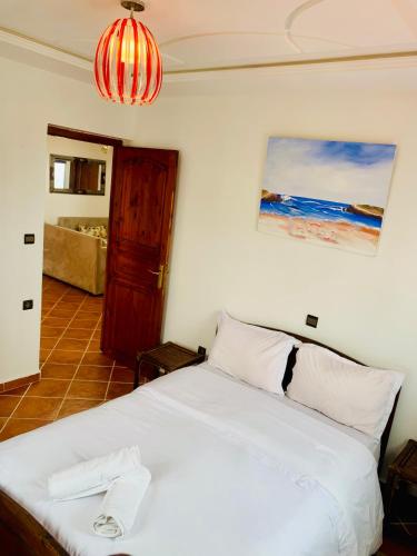a bedroom with a white bed and a room with a couch at Le grand château Vue sur Mer uniquement les familles in Oualidia