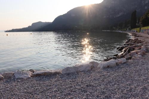 una spiaggia con il sole che riflette sull'acqua di Monika Holiday 5 Lake Garden a Garda