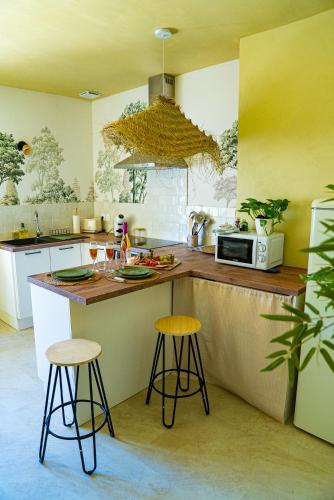 - une cuisine avec deux tabourets de bar et un four micro-ondes dans l'établissement Cinta Bali Suite romantique, à Cour-Cheverny