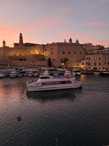 a group of boats docked in a harbor at sunset at Old refurbished Apartment in Bormla in Cospicua