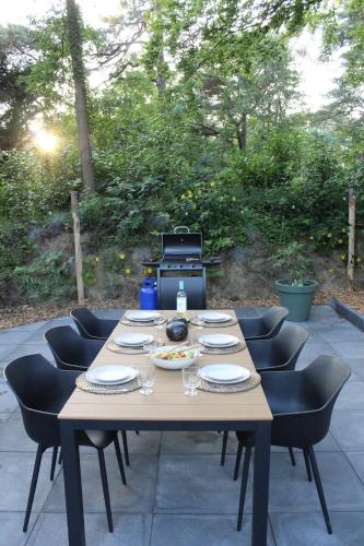 a wooden table with chairs and plates on it at Prachtige 4p wellness Kota in bos met Sauna en Hottub in Diever