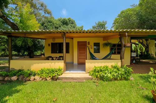 a small yellow house with a porch at Casinha Amarela - anexo ao Camping Pé na Jaca in Bonito