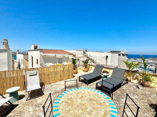 a patio with chairs and a table and the ocean at La Torretta - Marea Stays Collection in Otranto