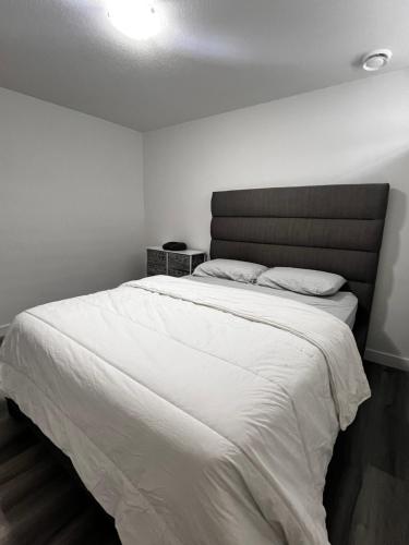 a bedroom with a large bed with white sheets at Cozy Corner - 1 bedroom suite - 15 mins from airport in Calgary