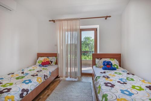 two beds in a room with a window at Villa Teodora, an ideal holiday hideaway for families and friends in Krapan
