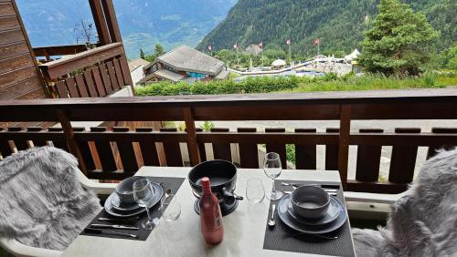 a table with plates and glasses on a balcony at Studio 4103 Les Sources aux Bains d'Ovronnaz in Ovronnaz