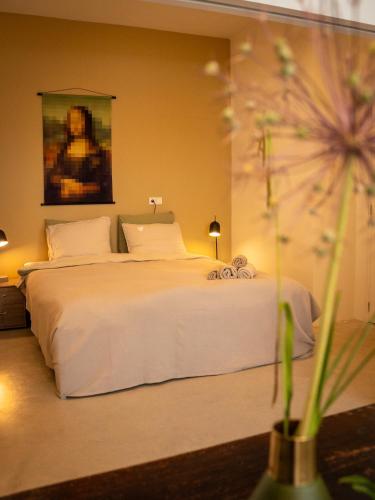 a bedroom with a white bed with a painting on the wall at Boetiek SimonS Loft appartement centrum Brummen in Brummen