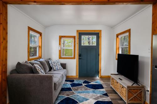 a living room with a couch and a tv at Arbutus Lake Cozy Cabin-Pontoon Rentals Available in Traverse City
