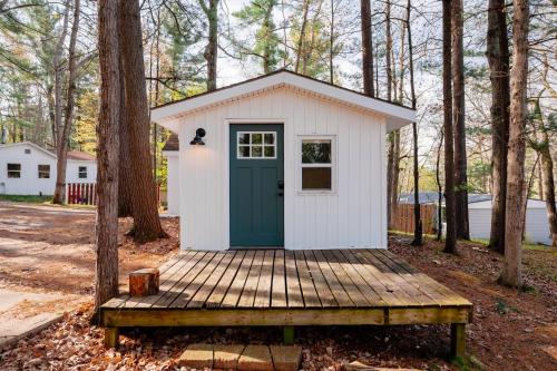 a small shed with a green door on a wooden deck at Arbutus Lake Cozy Cabin-Pontoon Rentals Available in Traverse City